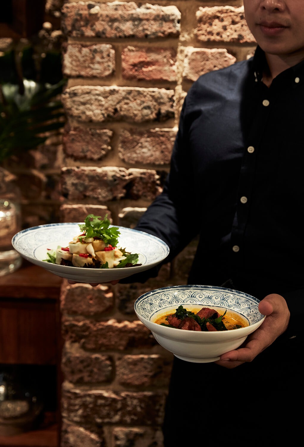 Server presenting curry and salad dishes